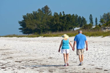 Holmes Beach, Anna Maria Adası, Fl / Amerika Birleşik Devletleri - 1 Mayıs 2018: kıdemli sabah erken çekerken elele çift sahilde yürümek. 