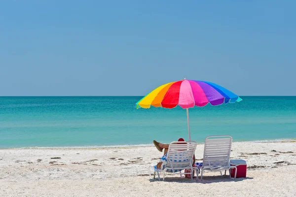 在海滩上享受阳光明媚的一天 不明身份的人在一把五颜六色的雨伞下放松 — 图库照片
