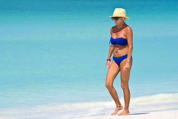Rijpe vrouw lopen op het strand — Stockfoto
