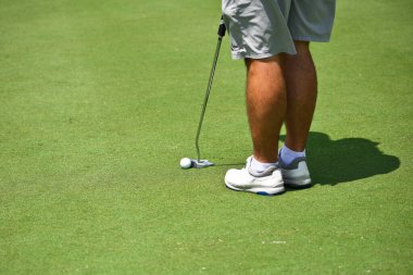 Golf Green 'deki genç adam atış yapmak için pozisyon alıyor.. 