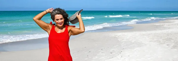 ビーチで赤い夏のドレスを着て美しい熟女 — ストック写真