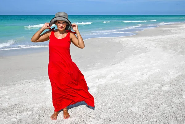 ビーチで赤い夏のドレスを着て美しい熟女 — ストック写真
