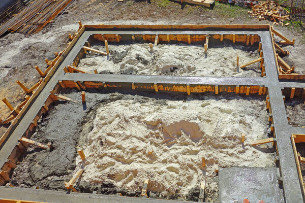 Liquid concrete is poured into the wooden form of the ribbon foundation