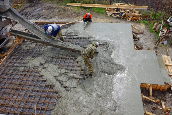 コンクリート ミキサー機械と労働者は 断熱材の上に横たわる補強にコンクリートを注ぐ の認識 — ストック写真