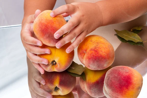 Ripe peaches and baby\'s hands on the mirror table