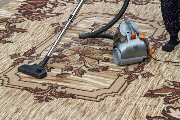 Kadın halı süpürüyor.