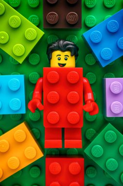Tambov, Rusya Federasyonu - 20 Mayıs 2018 yeşil baseplate arka planda bazı renkli Lego tuğla ile Lego kırmızı takım elbise tuğla adam minifigure. Stüdyo vurdu.