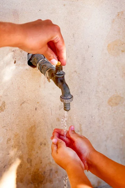 Woman hand open water tap and child washing his hands. Close up.