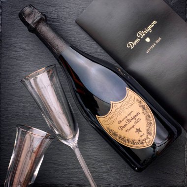 Tambov, Rusya Federasyonu - 16 Ağustos 2018 şişe şampanya Dom Perignon Vintage 2005 yılının iki kadehlerin ve siyah taş zemin üzerine kitapçık ile. Stüdyo vurdu.