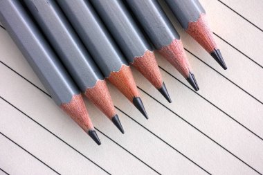 Üst üste çizgili kağıt arka plan üzerinde gri grafit kalem.