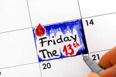 Kadın parmakları hatırlatma takviminde Friday The 13th yazma kalemi ile. Yakın çekim.