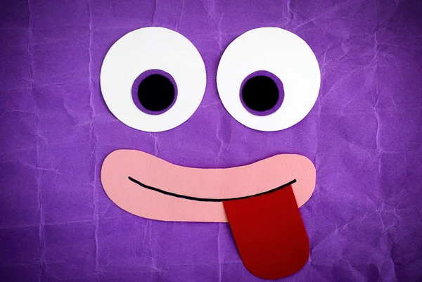 舌を突き出してで変な顔 感情的な面は紙製です 紫色の背景 — ストック写真
