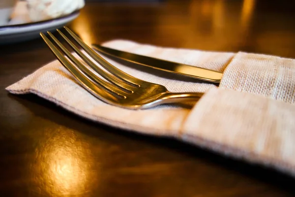 Вилка и нож в льняной салфетке на столе . — стоковое фото