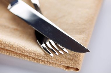 çatal ve bıçak üzerinde bej renkli peçete.