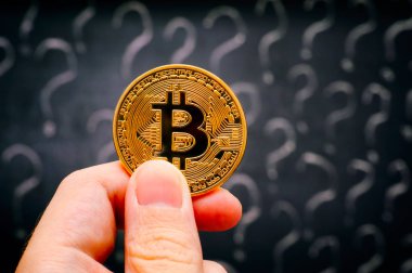 Kişi el blackboard soru işaretleri ile karşı altın Bitcoin sanal para ile. Yakın çekim.
