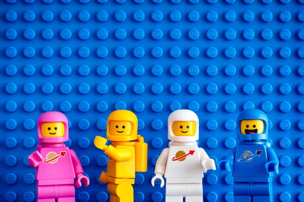 Four Lego astronaut minifigures against blue baseplate backgroun — Stock Photo, Image