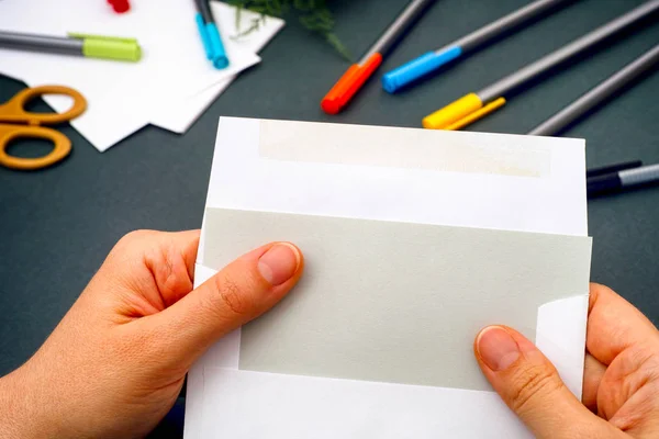 Mujer mano sacando papel gris del sobre . — Foto de Stock