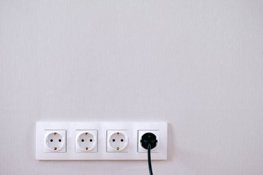 Dört güç yuva, siyah kurşun ve gri duvar üzerinde fiş. 