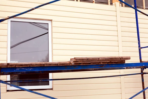 Byggnadsställningar runt huset nära vägg med fönster och beige rangerbangård — Stockfoto