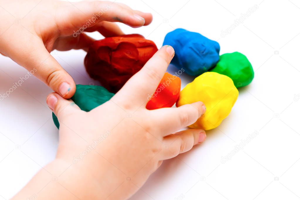 Child hands playing with play clay balls.