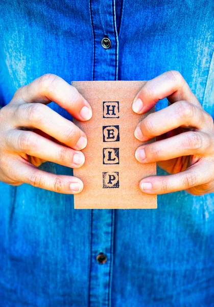 Woman hands holding cardboard card with words Help made by black — Stock Photo, Image