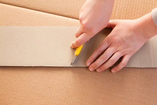 Cuchillo de papel en persona manos corte pedazo de cartón . — Foto de Stock