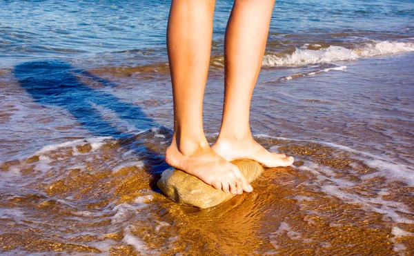 Donna a piedi nudi in piedi sulla pietra nel mare . — Foto Stock