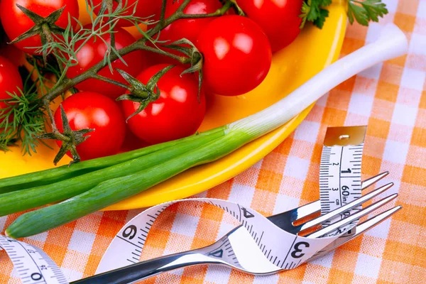 Yellow plate with cherry tomatoes and green onion and fork with — Stock Photo, Image