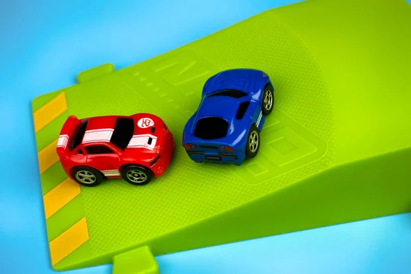 Two Nano Speed Micro Cars on green springboard on blue backgroun — Stock Photo, Image