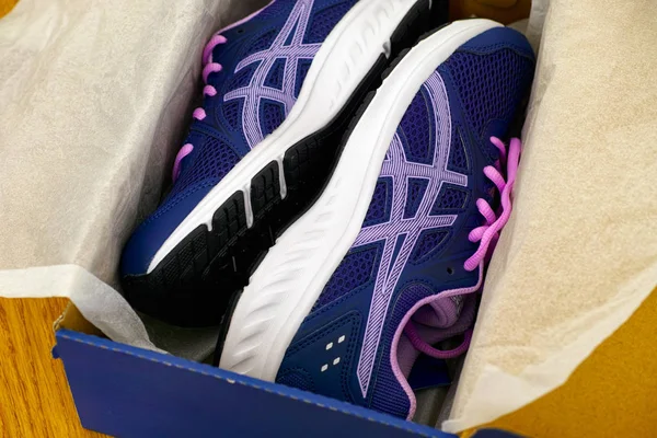 Novos Asics azuis tênis de corrida na caixa. Fundo de madeira . — Fotografia de Stock