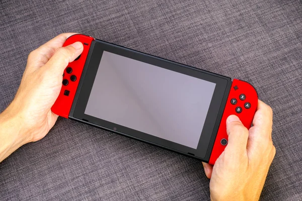 Mãos de pessoa segurando Nintendo Switch console de videogame . — Fotografia de Stock