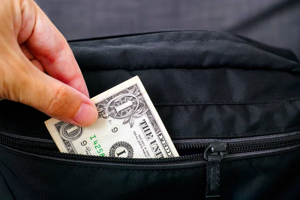 Persoon hand het nemen van geld uit zwarte tas. — Stockfoto