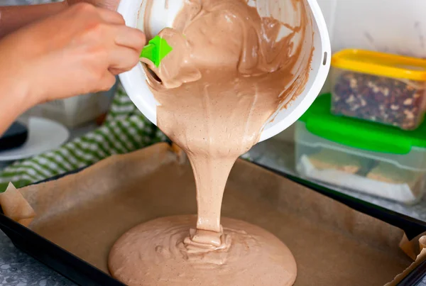 Женщина руки с лопаткой положить шоколадное тесто на поднос для выпечки . — стоковое фото