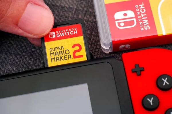 Person fingers inserting Super Mario Maker 2 video game cartridg — Stock Photo, Image