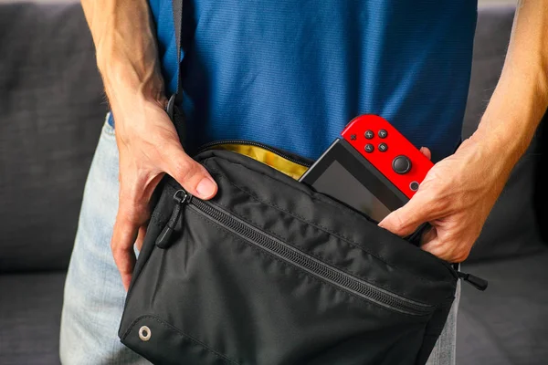 Mann nimmt Nintendo-Switch-Videospielkonsole aus schwarzer Tasche. — Stockfoto
