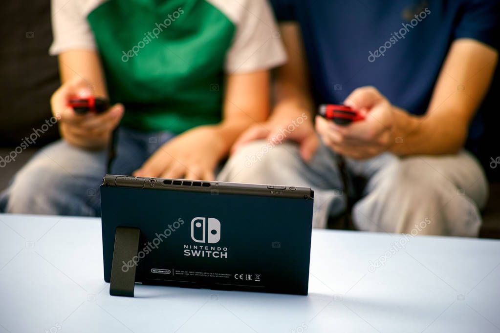 Tambov, Russian Federation - June 22, 2019 Man and kid playing Nintendo Switch video game console.