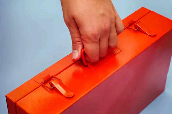 Person hand med orange metall låda. Blå bakgrund. — Stockfoto