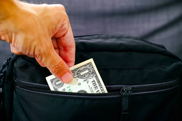 Człowiek ręka biorąc na zewnątrz pieniądze z czarny torba. — Zdjęcie stockowe