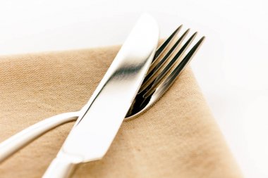 Bej peçete üzerinde masa bıçağı ve çatal. 