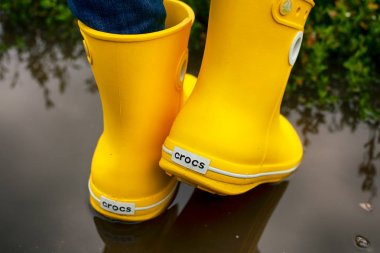 Su birikintisi sarı Crocs çizmeler kadın bacaklar.