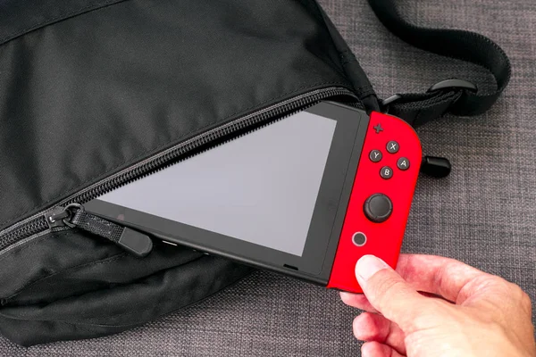 Person hand taking out Nintendo Switch video game console from b — Stock Photo, Image