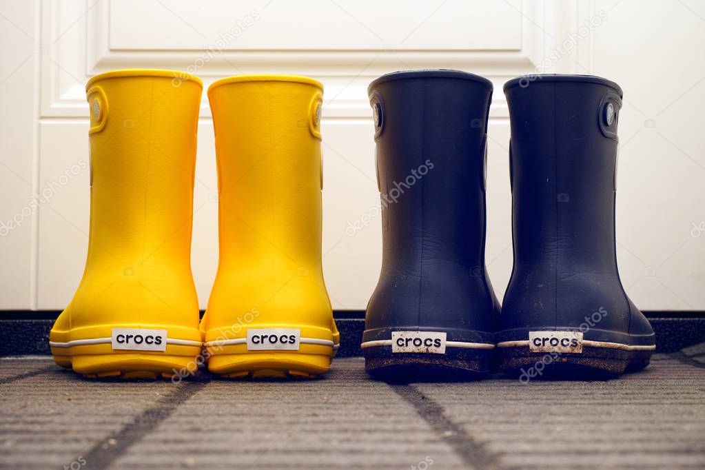 Tambov, Russian Federation - August 08, 2019 Two pair of Crocs rubber boots standing in hallway near door.