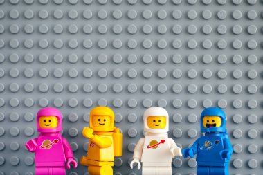 Gri taban plakası backgroun karşı dört Lego astronot minifigures
