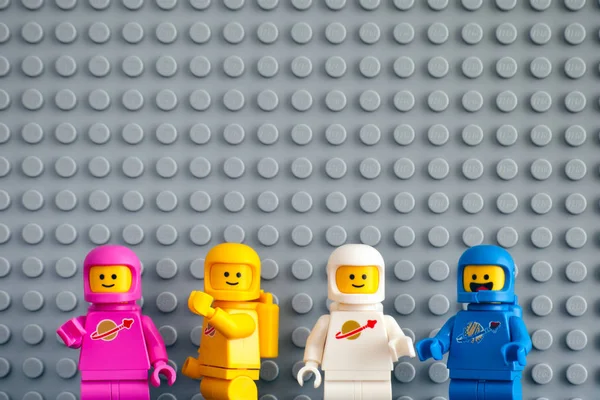 Four Lego astronaut minifigures against gray baseplate backgroun — Stock Photo, Image