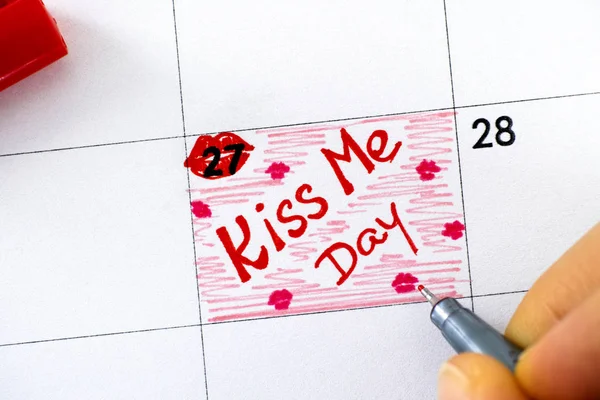 Женщина пальцы с ручкой написания напоминание поцелуй меня день в календаре . — стоковое фото