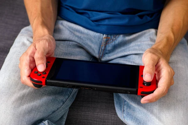 Mann sitzt auf Sofa und spielt Nintendo Switch Videospielkonsole — Stockfoto