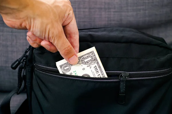 Mano de persona sacando un billete de un dólar de la bolsa negra . — Foto de Stock