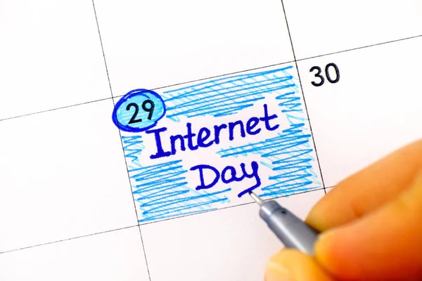 Palce kobiety z długopisem przypominającym Internet Day w kalendarzu — Zdjęcie stockowe