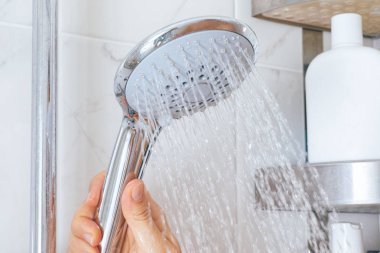 Kadın eli banyoda duş başlığı kullanıyor.. 