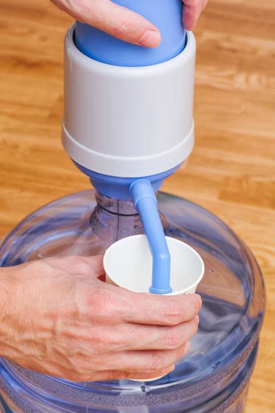 Person hands pouring water in paper cup from bottle with pump — Stock Photo, Image